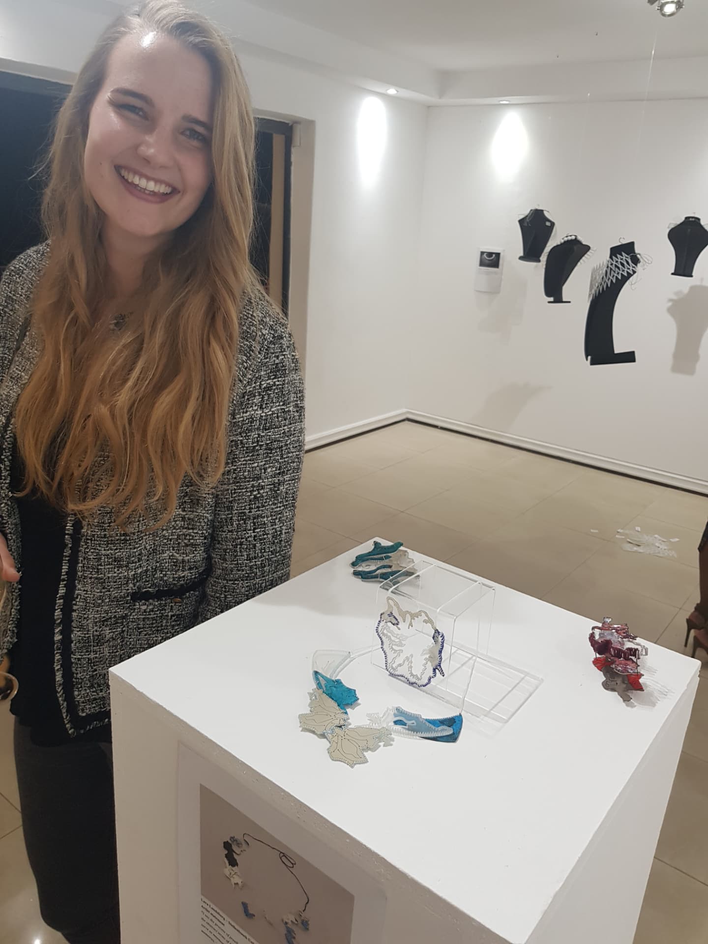 Lara Landsberg beside a plinth of her award-winning contemporary art jewellery at the South African Contemporary Jewellery Week exhibition.