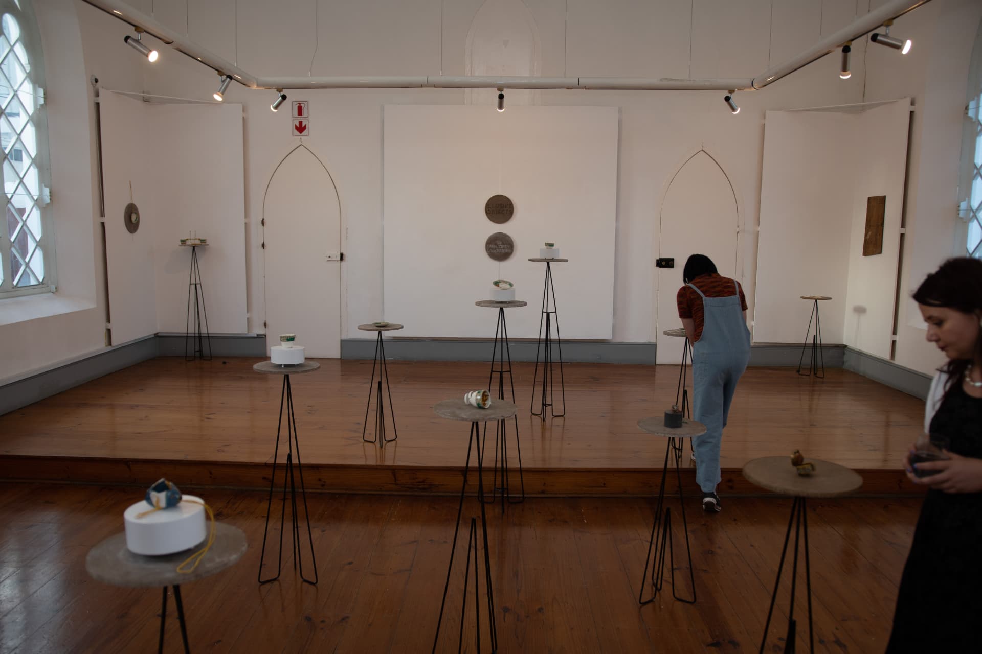 Install view of the Master of Visual Arts exhibition at Gus Gallery, Stellenbosch — porcelain and mixed-media jewellery on slender concrete-topped plinths.