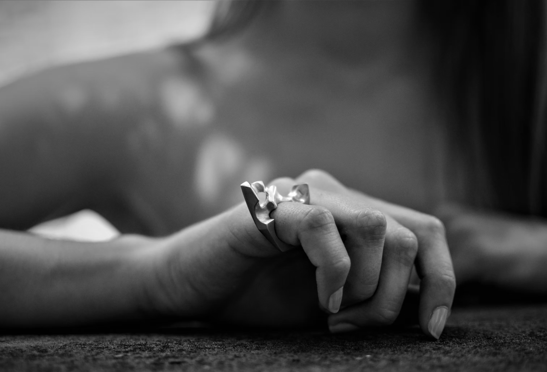 Hand wearing a sculptural gold ring with a sapphire